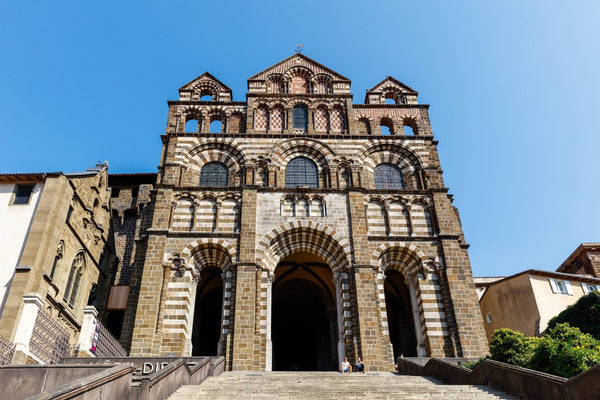 Façade polychrome romane de la cathédrale Notre-Dame du Puy-en-Velay, en pierres alternées sombres et claires.